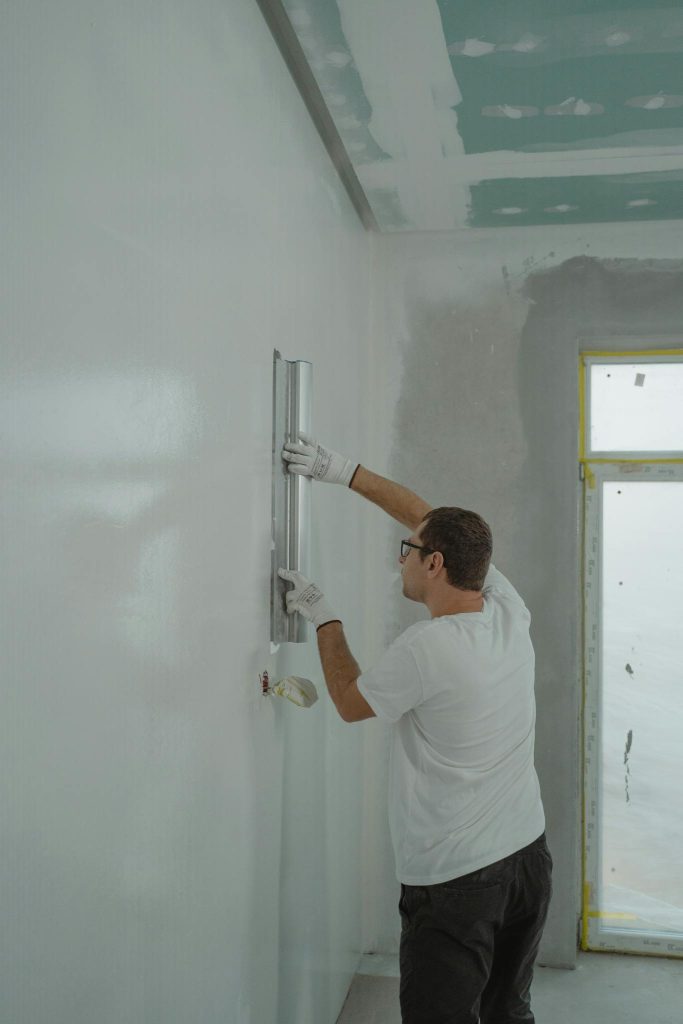 Adult male painting interior walls white in a house renovation project.