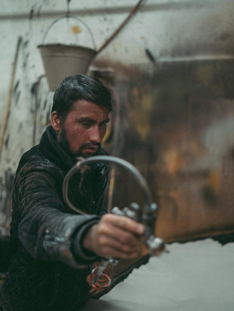 Focused industrial worker using a spray gun in a workshop setting, demonstrating hands-on craftsmanship.