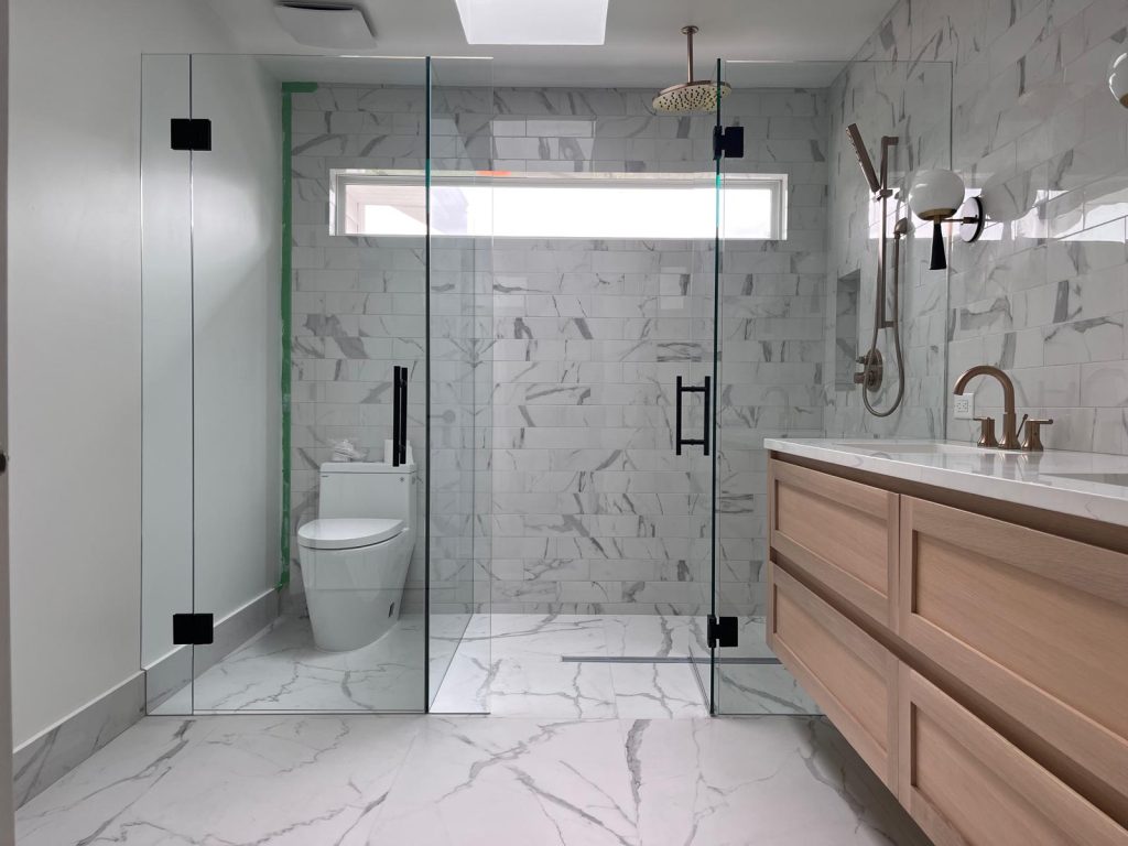 Freshly painted modern bathroom with clean white walls, frameless glass shower, marble-look tile, floating wood vanity, and a bright, polished finish.