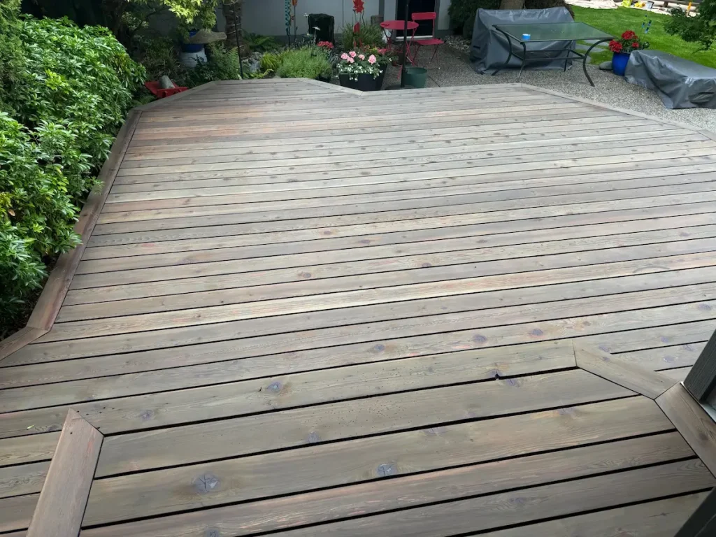 Wide view of a large exterior wood deck with weathered boards, showing the surface cleaned and prepared for sanding, staining, or refinishing.