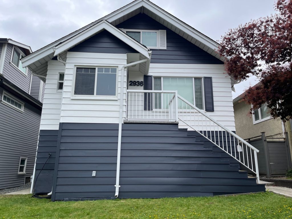 Front view of a freshly painted house exterior featuring deep blue and white siding, white trim, dark shutters, and a large front staircase. Another title option: Striking Exterior Transformation with Crisp Contrast and Curb Appeal