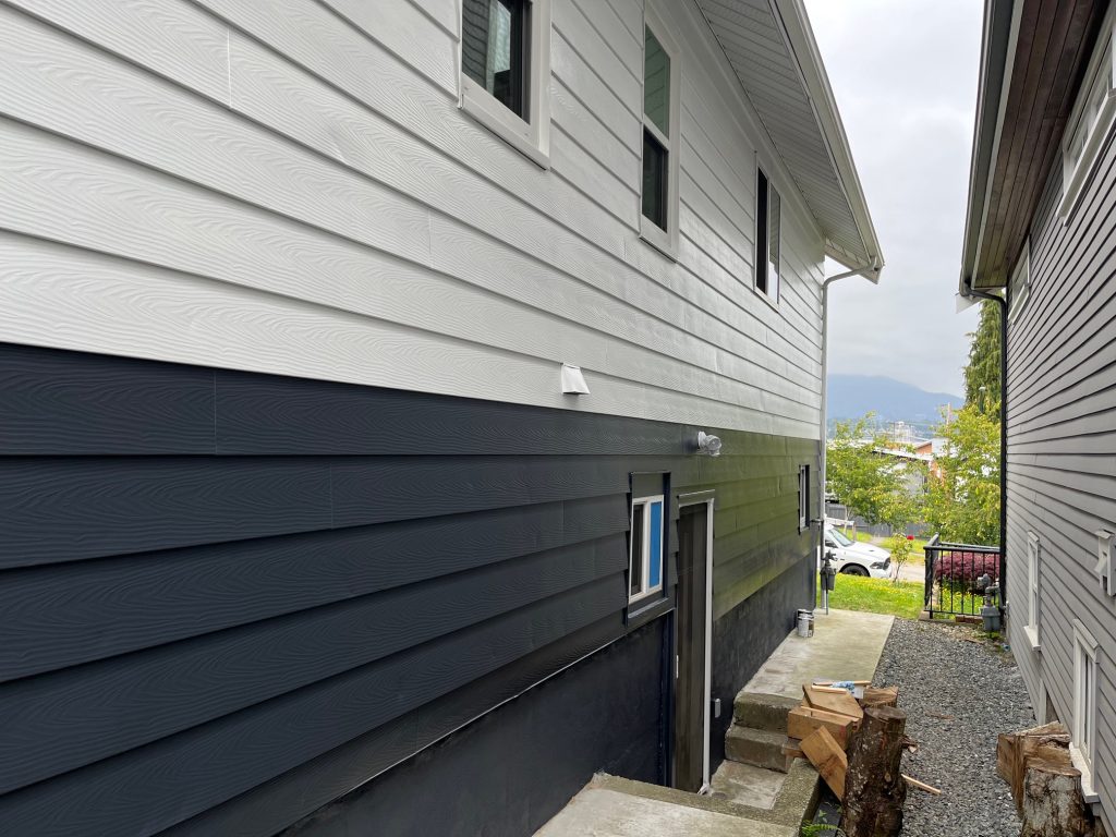 Freshly painted exterior siding in Port Moody with crisp white upper walls and dark charcoal lower siding on a residential home