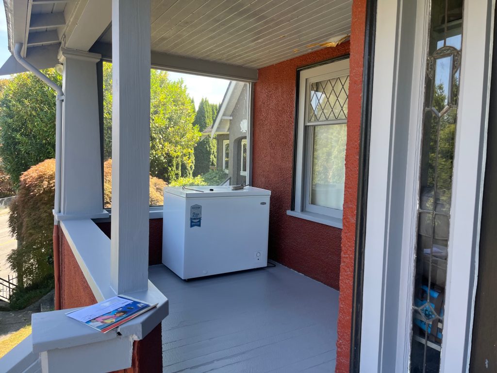 Freshly painted front porch with grey floor, white trim and railings, and updated exterior details on a character home in Port Moody